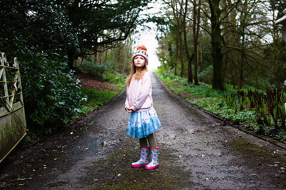 Young girl stands in woodland path gazing skywards