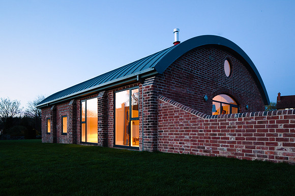 A curved roofed building at dusk