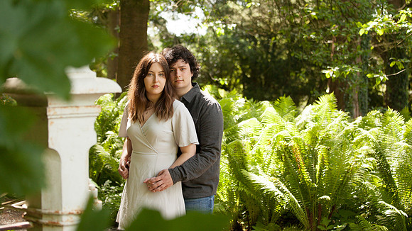 A couple are photographed in a woodland with ferns in the background